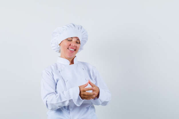 Foto gratuita mujer rubia frotándose las manos en uniforme de cocinero blanco y luciendo bonita