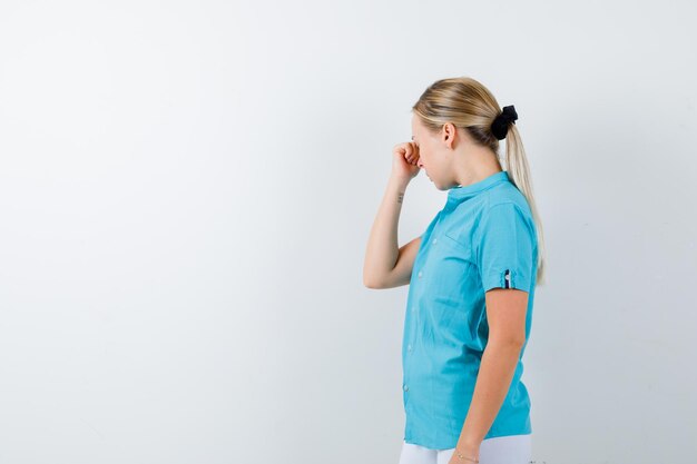 Mujer rubia frotándose los ojos y la nariz en una blusa azul y mirando agotado aislado