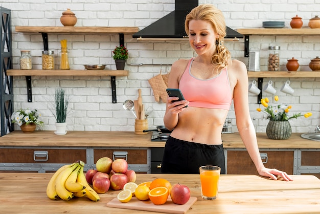 Mujer rubia con frutas en la cocina