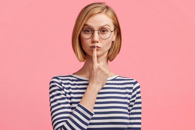 Mujer rubia con gafas redondas y blusa a rayas