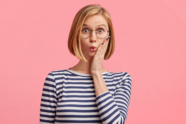 Mujer rubia con gafas redondas y blusa a rayas