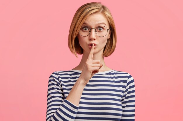 Mujer rubia con gafas redondas y blusa a rayas