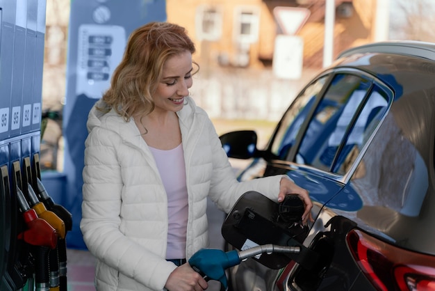 Mujer rubia en la gasolinera con su coche