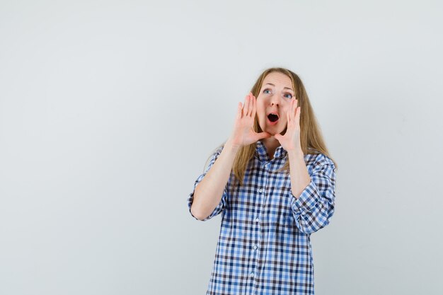 Mujer rubia gritando o anunciando algo en camisa y mirando emocionado,