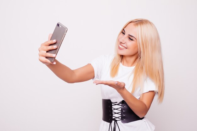 Mujer rubia haciendo selfie en aislado