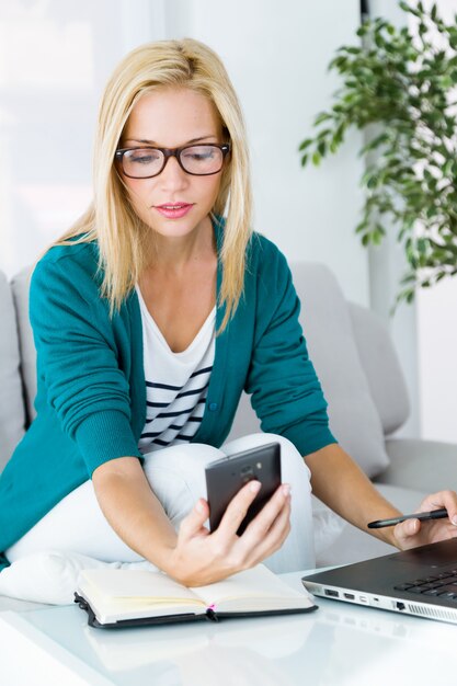 La mujer rubia hermosa usando el teléfono