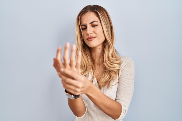 Foto gratuita mujer rubia joven de pie sobre un fondo aislado que sufre dolor en las manos y los dedos inflamación de la artritis