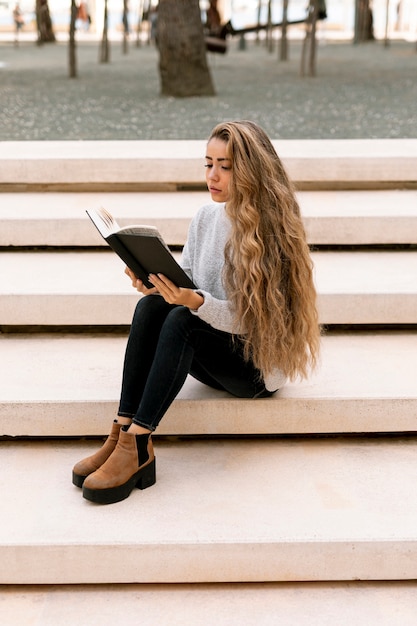 Foto gratuita mujer rubia leyendo afuera