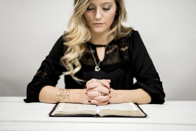 Mujer rubia leyendo la Biblia y rezando