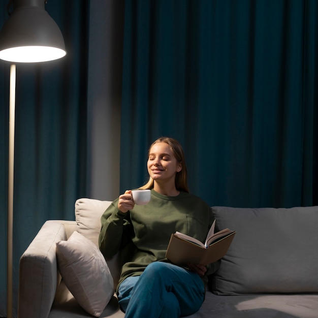 Mujer rubia leyendo un libro en el sofá