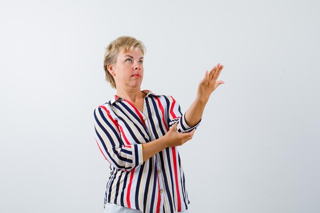 Mujer rubia madura en una camisa de rayas verticales