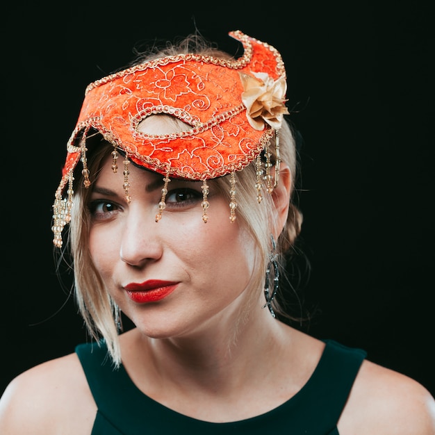 Foto gratuita mujer rubia en máscara de carnaval naranja