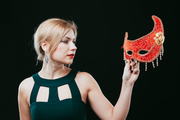 Foto gratuita mujer rubia mirando máscara de carnaval rojo