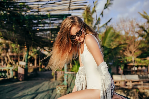 Mujer rubia de moda en traje de baño blanco en lugar exótico