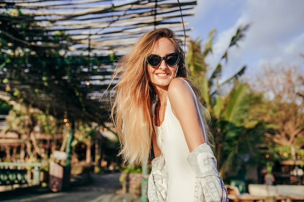 Mujer rubia de moda en traje de baño blanco en lugar exótico