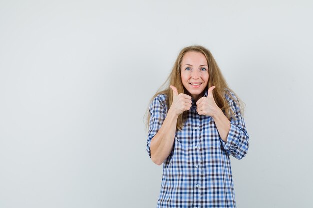 Mujer rubia mostrando doble pulgar hacia arriba en camisa y mirando feliz,