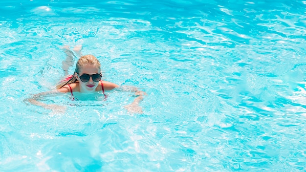 Mujer rubia nadando en la piscina