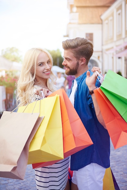 Mujer rubia con novios sosteniendo bolsas de la compra.