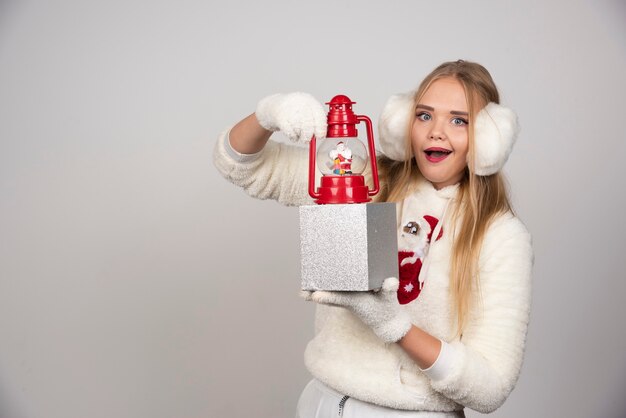 Mujer rubia en oreja blanca mostrando regalo de Navidad.