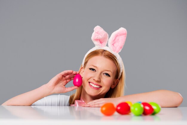 Mujer rubia con orejas de conejo y huevos de pascua