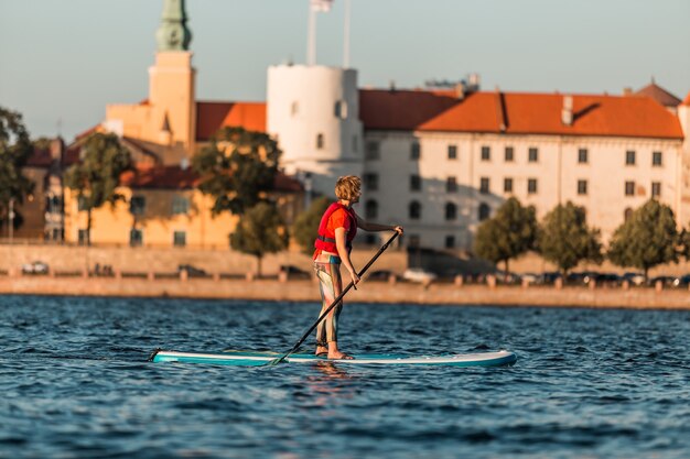 Mujer rubia en paddleboard en el casco antiguo de Riga, Letonia