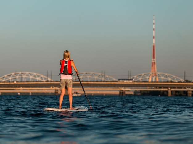 Mujer rubia en paddleboard en el río Daugava, Letonia