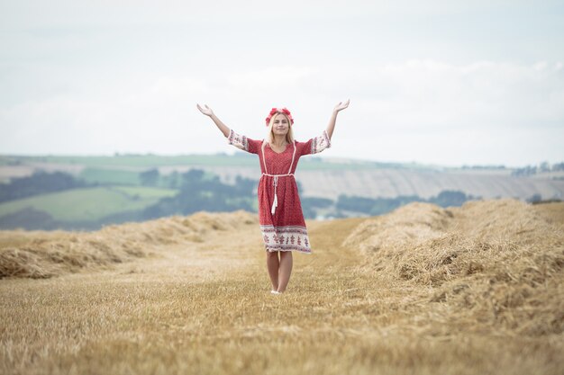 Mujer rubia de pie en el campo con los brazos abiertos