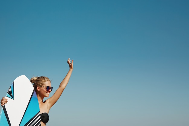 Mujer rubia en la playa con tabla de surf