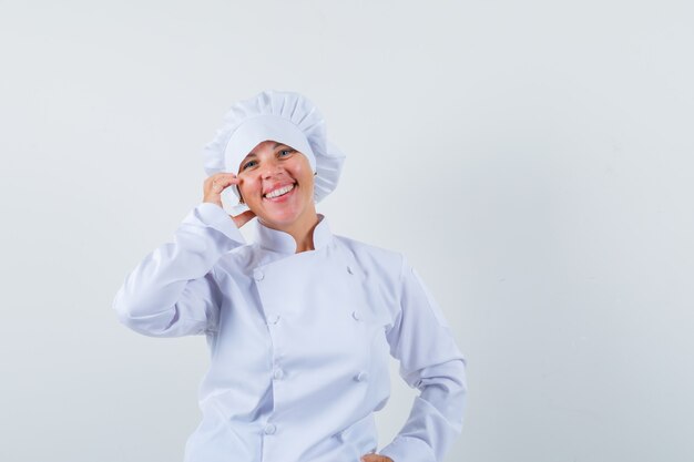 Mujer rubia poniendo la mano en la mejilla en uniforme de cocinero blanco y luciendo bonita