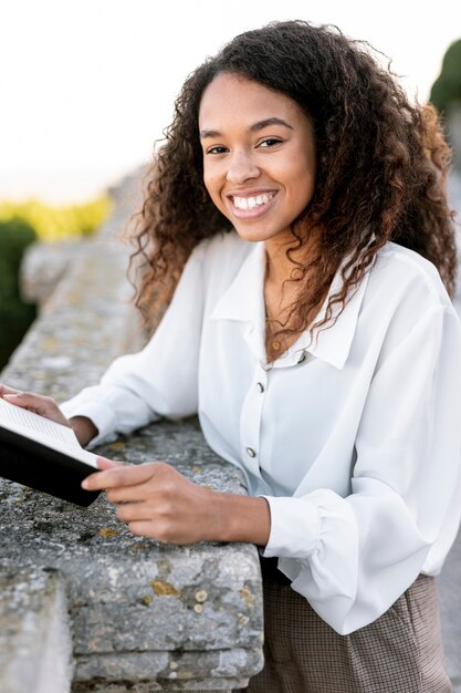 Mujer rubia posando al aire libre mientras sostiene un libro