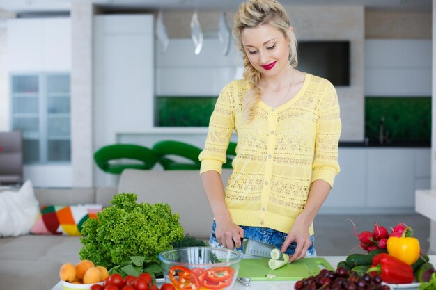 mujer rubia preparar ensalada en la cocina