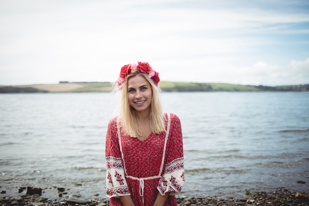 Foto gratuita mujer rubia que llevaba una tiara de flores sentada cerca de un río