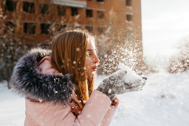 Mujer rubia que sopla nieve de las manos