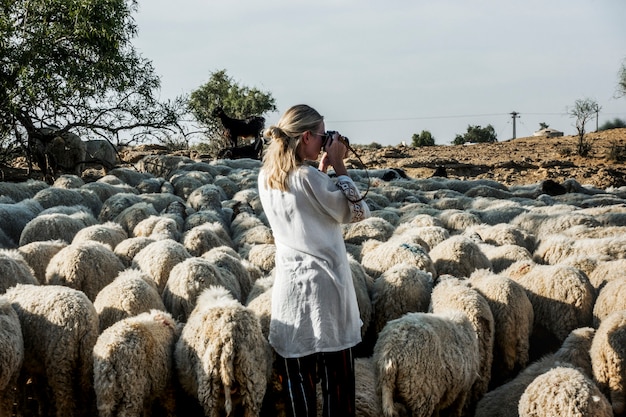 Mujer rubia entre un rebaño de ovejas