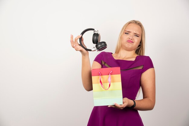 Mujer rubia sacando auriculares de la bolsa.