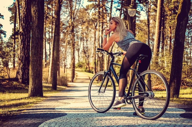 Mujer rubia sexy en bicicleta en un parque de verano