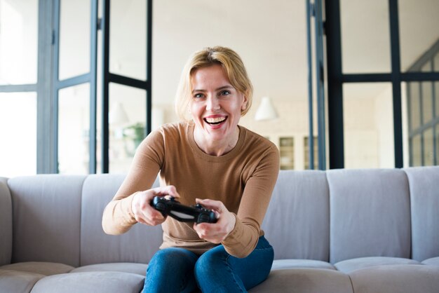 Mujer rubia en el sofá jugando consola de juegos