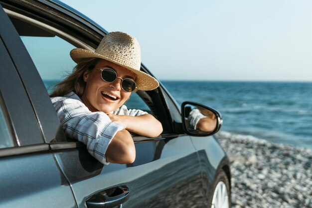 Mujer rubia con sombrero mirando por la ventana del coche