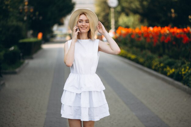 Mujer rubia en sombrero usando teléfono