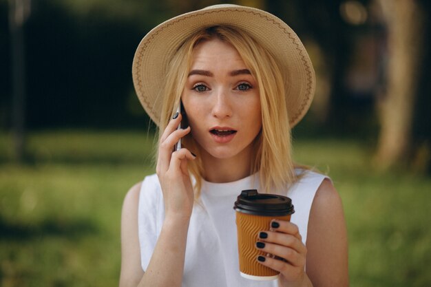 Mujer rubia en sombrero usando teléfono