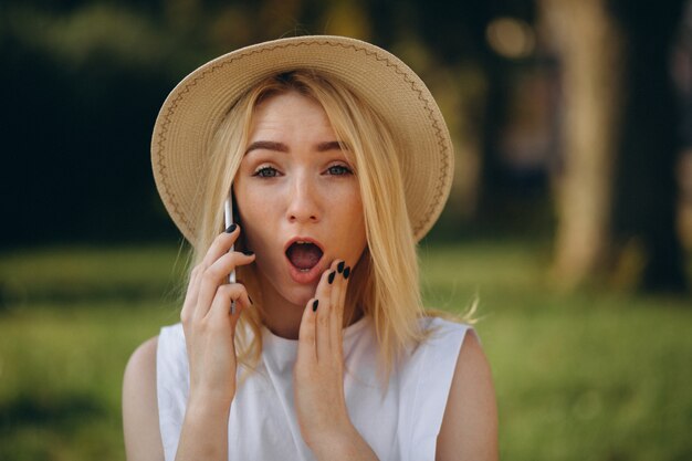 Mujer rubia en sombrero usando teléfono