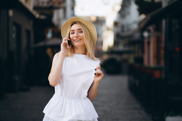 Mujer rubia en sombrero usando teléfono