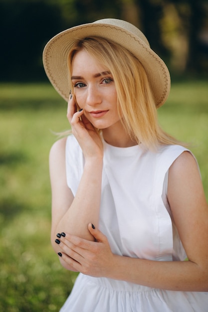 Mujer rubia en sombrero y vestido blanco