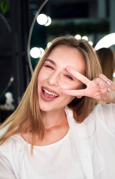 Mujer rubia sonriendo y haciendo el signo de la paz