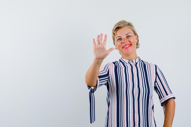 La mujer rubia sonriente muestra el gesto número cinco con la mano en el fondo blanco