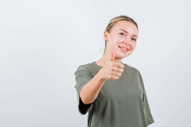 La mujer rubia sonriente muestra un gesto perfecto con el pulgar en el fondo blanco