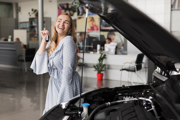 Mujer rubia sonriente que sostiene llaves del coche