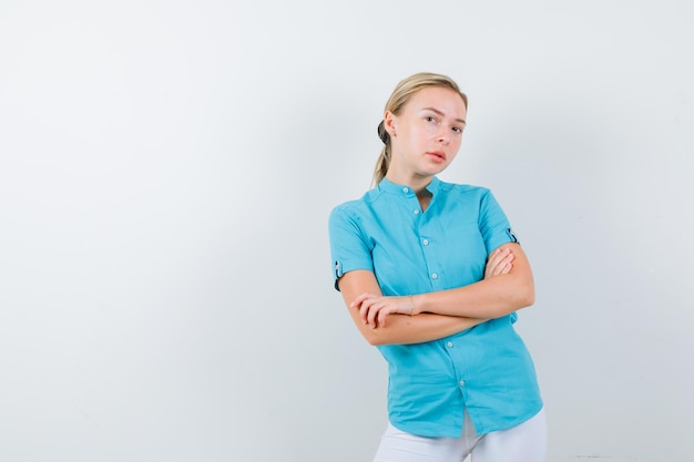 Mujer rubia sosteniendo los brazos cruzados en blusa azul y mirando confiado aislado