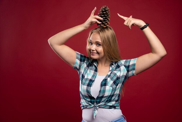 La mujer rubia sostiene el cono de roble en la cabeza y se siente positiva.