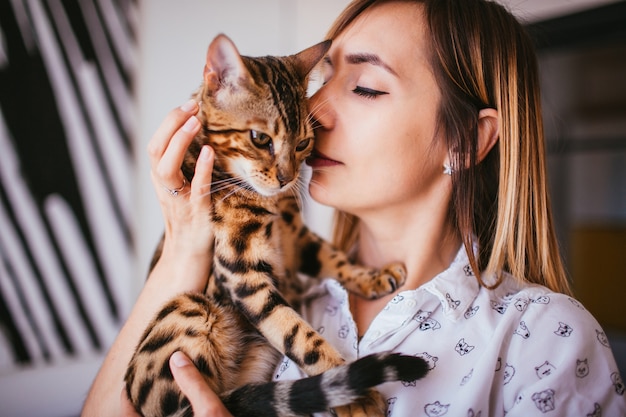 La mujer rubia sostiene un gato de Bengala